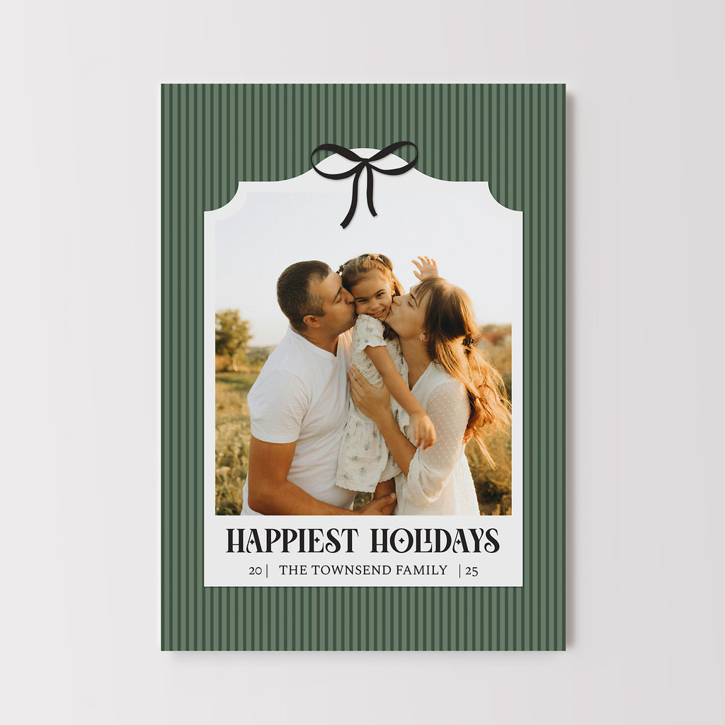 Holiday card with a green pinstriped background, a single photo framed with a white elegant frame, black text and black bow detail