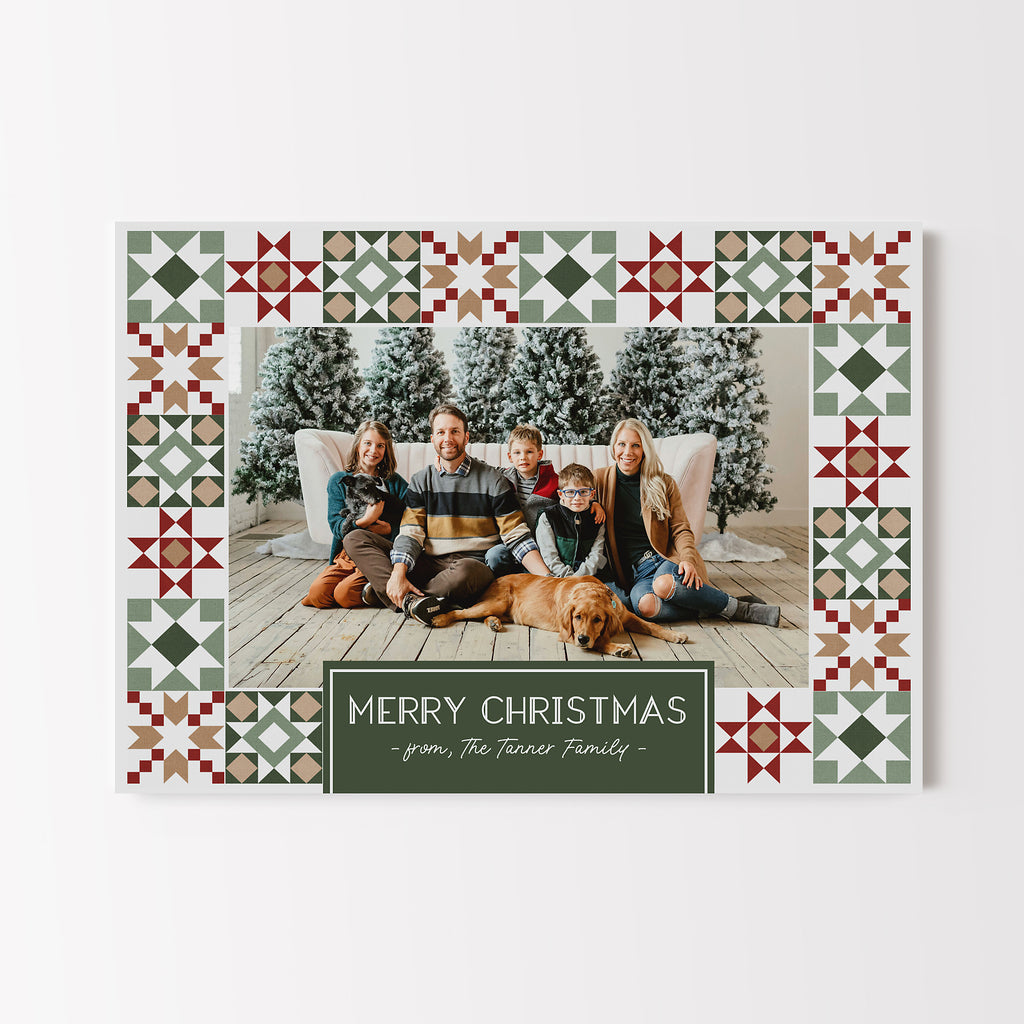Christmas card in a landscape format with a single photo framed by a quilted Christmas star pattern in red green and gold colors. 